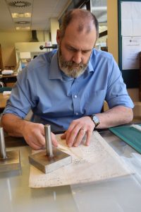 Nick Sellwood, Senior Conservator at NRO, carrying out repair work to a page of the Great Yarmouth parish register.